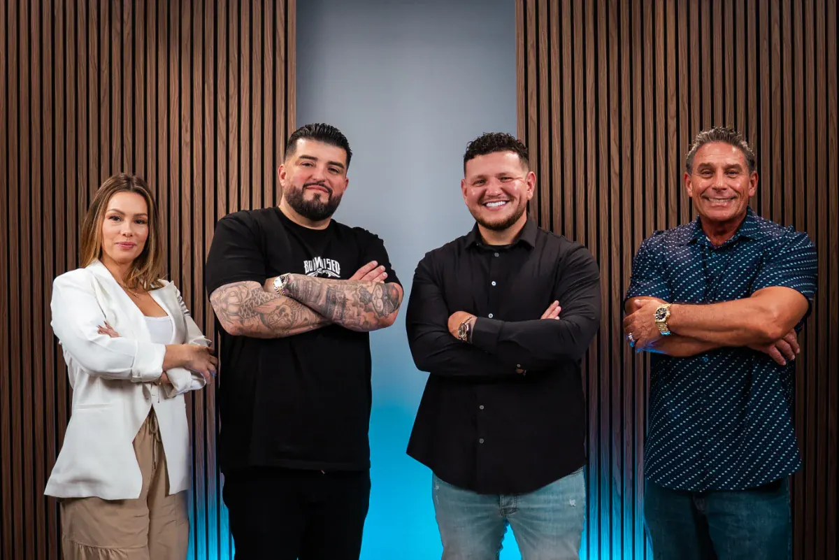 Four clients standing confidently against a wooden backdrop